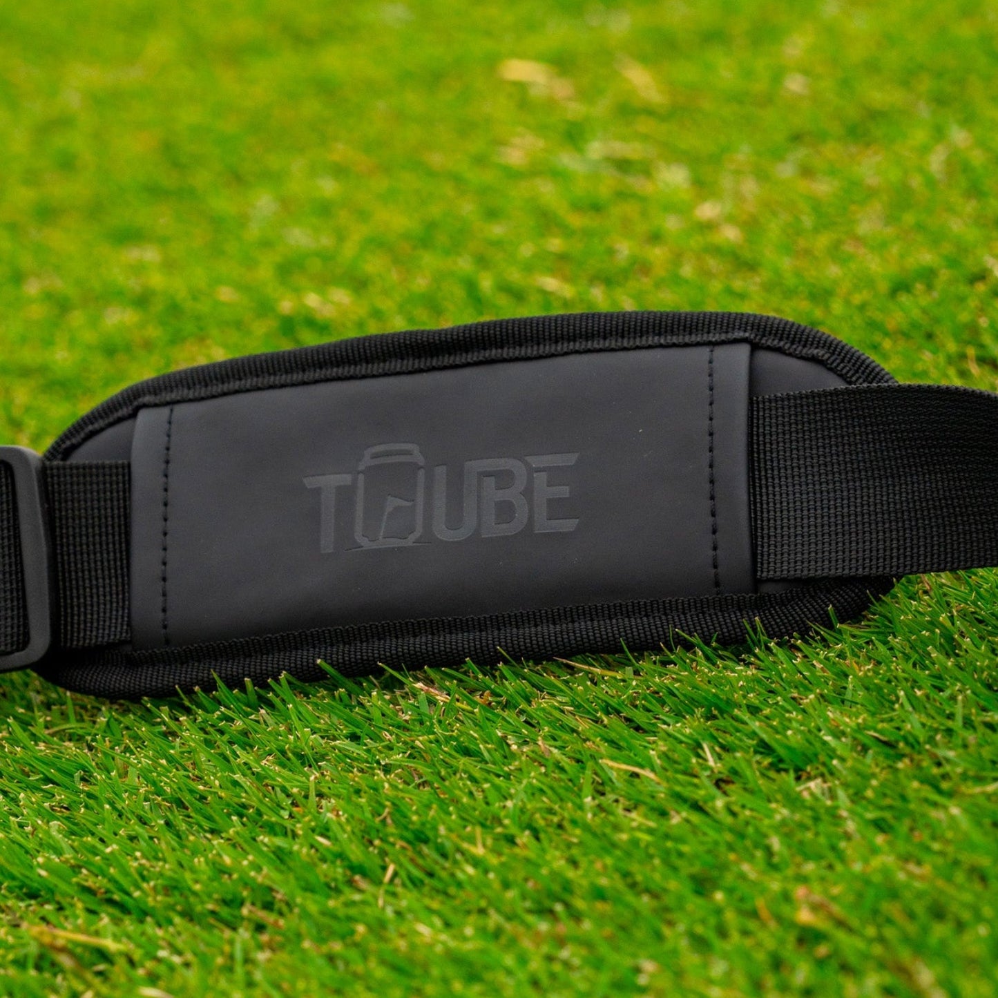 Tuube embossed shoulder strap - strap laying on grass.