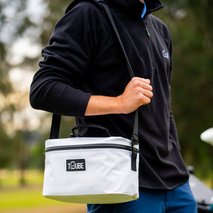 Tuube shoulder strap attached to a Tuube Lunch Box 6L white cooler, hands-free carry demonstrated on course, padded nylon construction