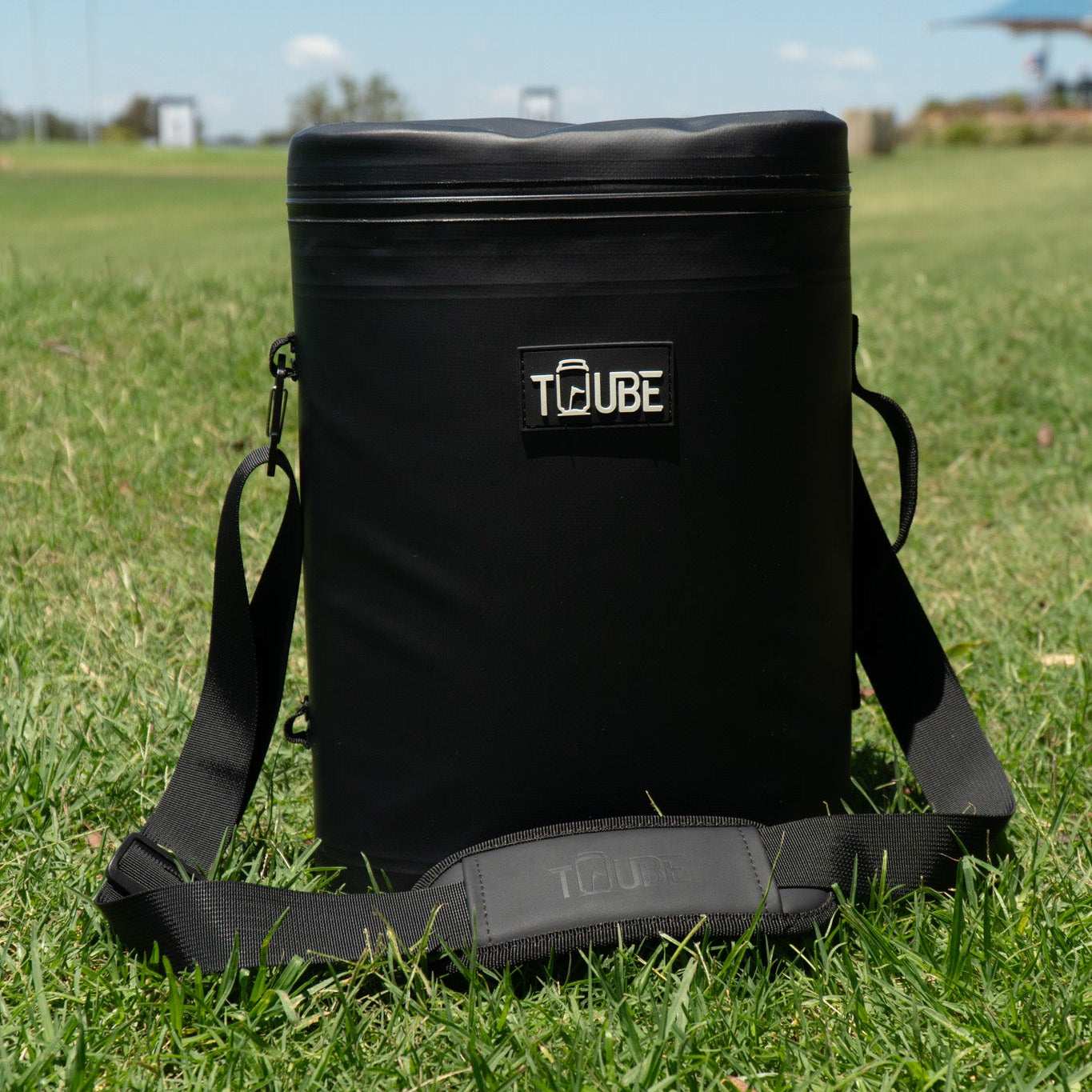 Tuube Weekender 8L black cooler bag worn with included carry strap over shoulder, ideal for golf travel, beach days, and weekend trips