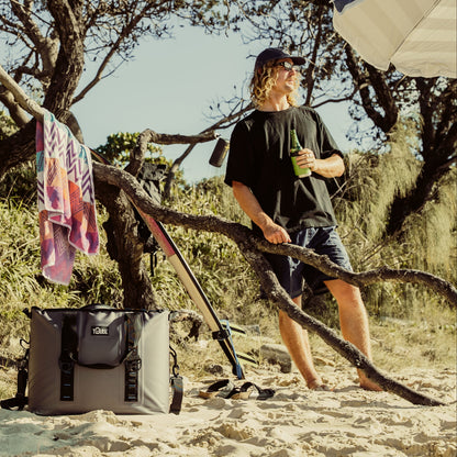 Green Tuube stainless steel cooler on a beach, paired perfectly with a Tuube 36L Traveller
