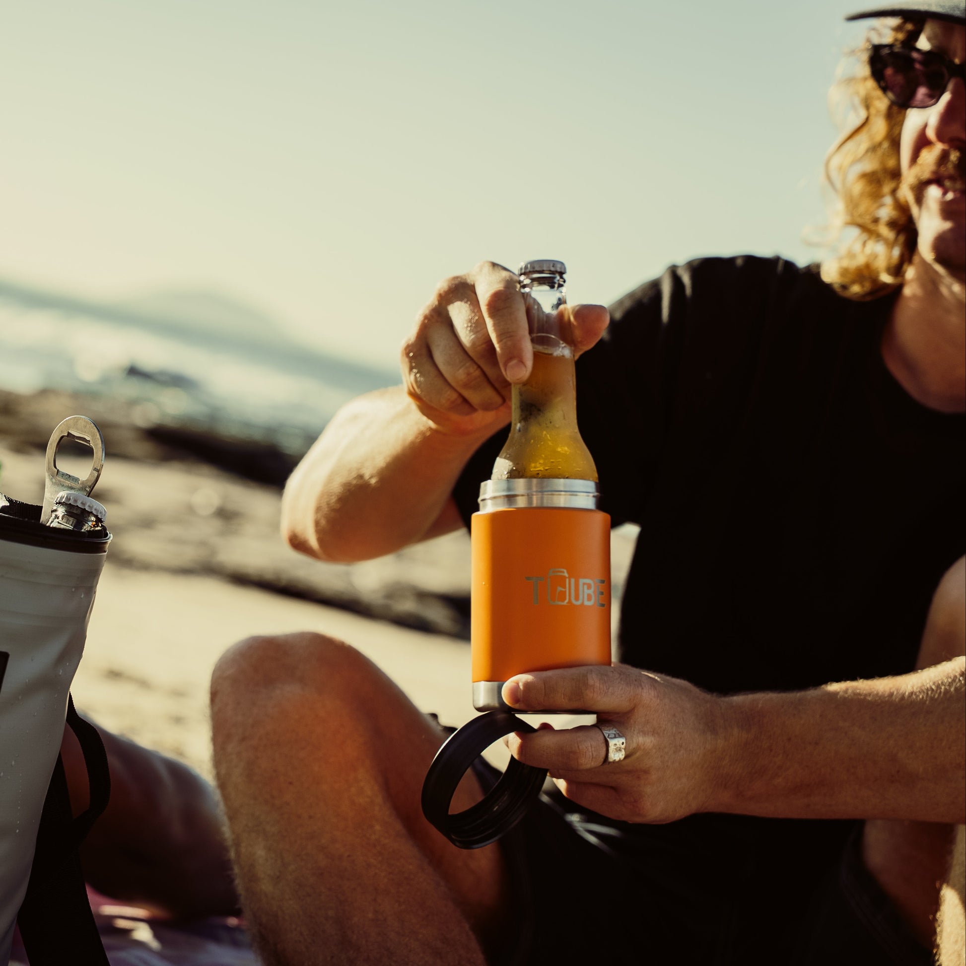 Orange Tuube stainless steel cooler held showing compact cup holder size, insulated no-condensation golf drink cooler