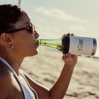 White Tuube stainless steel cooler held by a beachgoer, showing compact size that fits standard bottles and cans