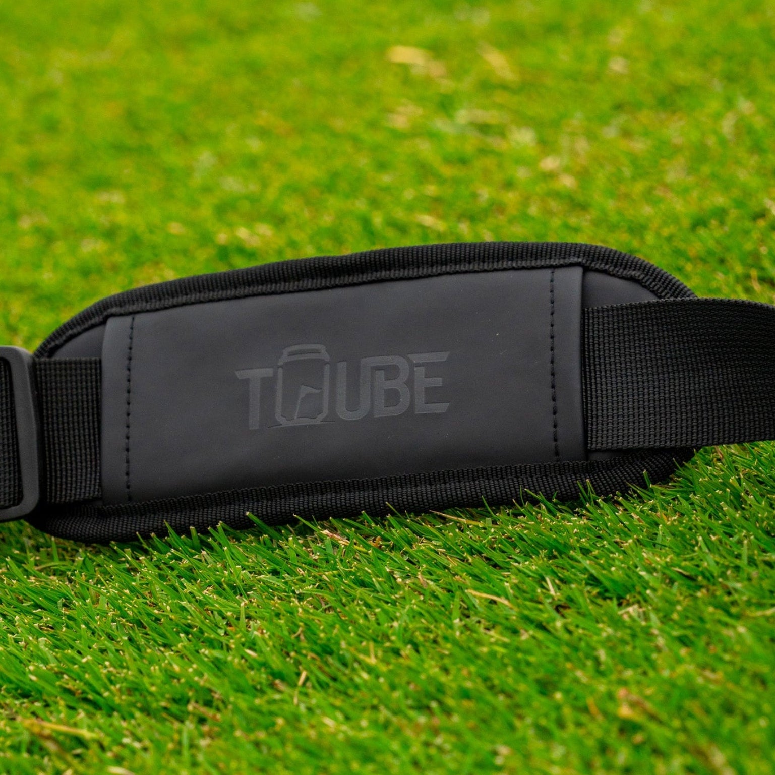 Tuube embossed shoulder strap - strap laying on grass. 