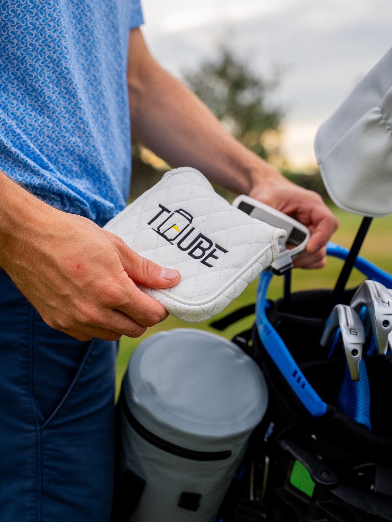 Tuube Putter Head Cover - Golfer removing putter cover. 