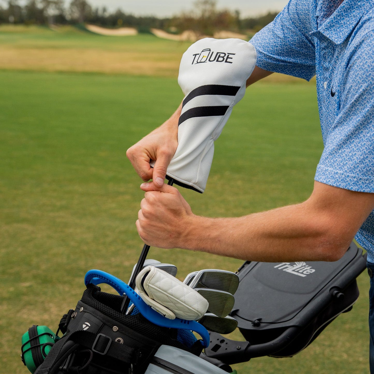 Golfer placing Tuube driver head cover onto a driver club, showing easy snug-fit installation and premium material construction