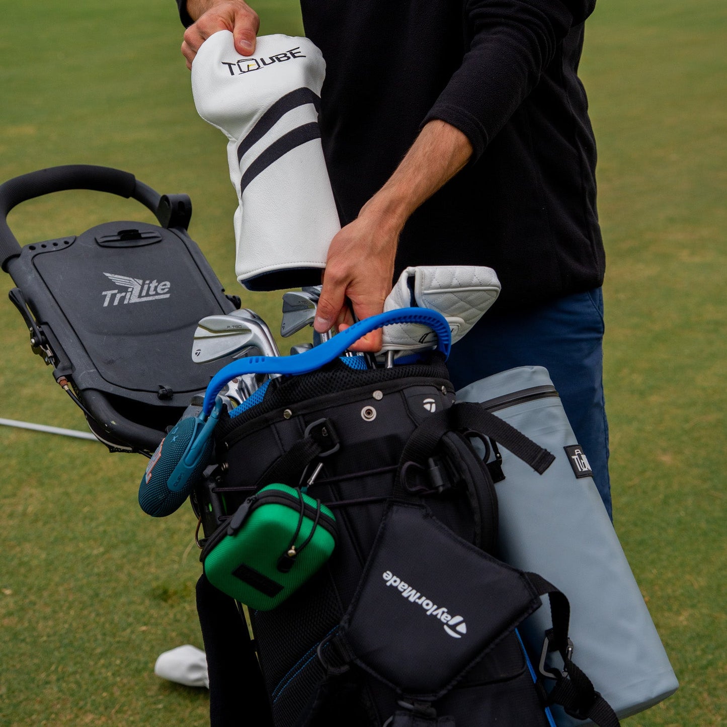 Tuube fairway wood cover being placed on a club on course, showing easy-fit sock design and branded soft lining for protection