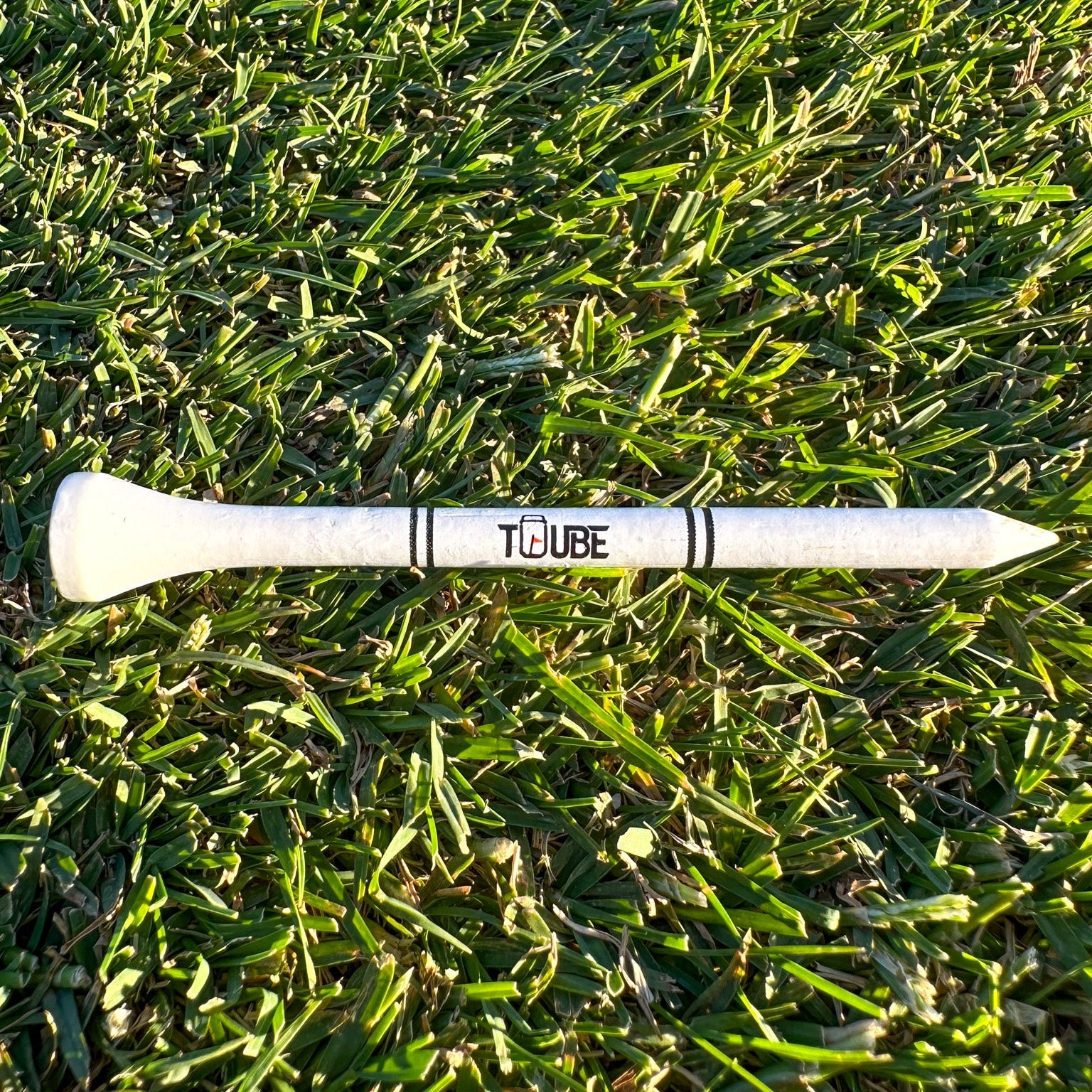 Tuube 83mm long golf tees scattered on a golf course, showing durable bamboo construction and consistent driver tee height