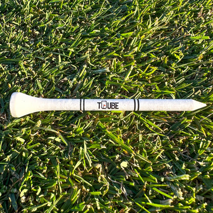 Tuube 83mm long golf tees scattered on a golf course, showing durable bamboo construction and consistent driver tee height