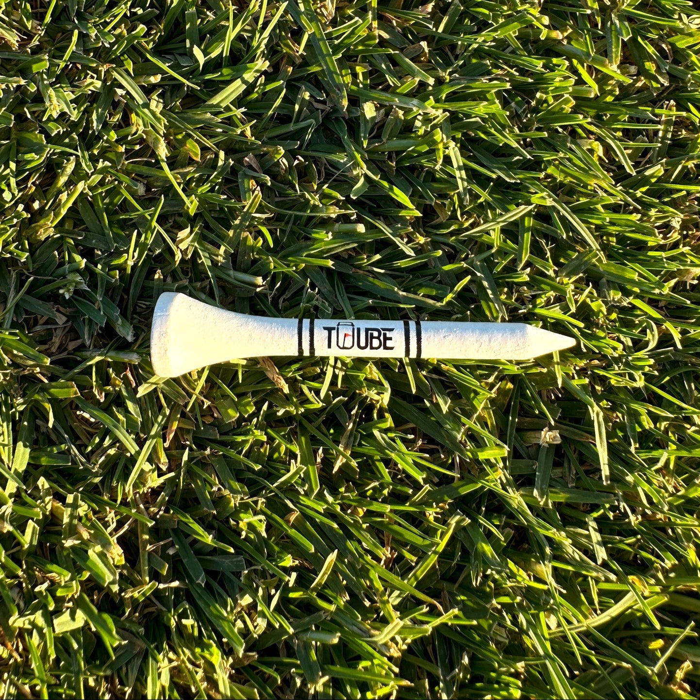 Tuube short 54mm tee inserted in turf, demonstrating lower tee height for irons with durable plastic construction