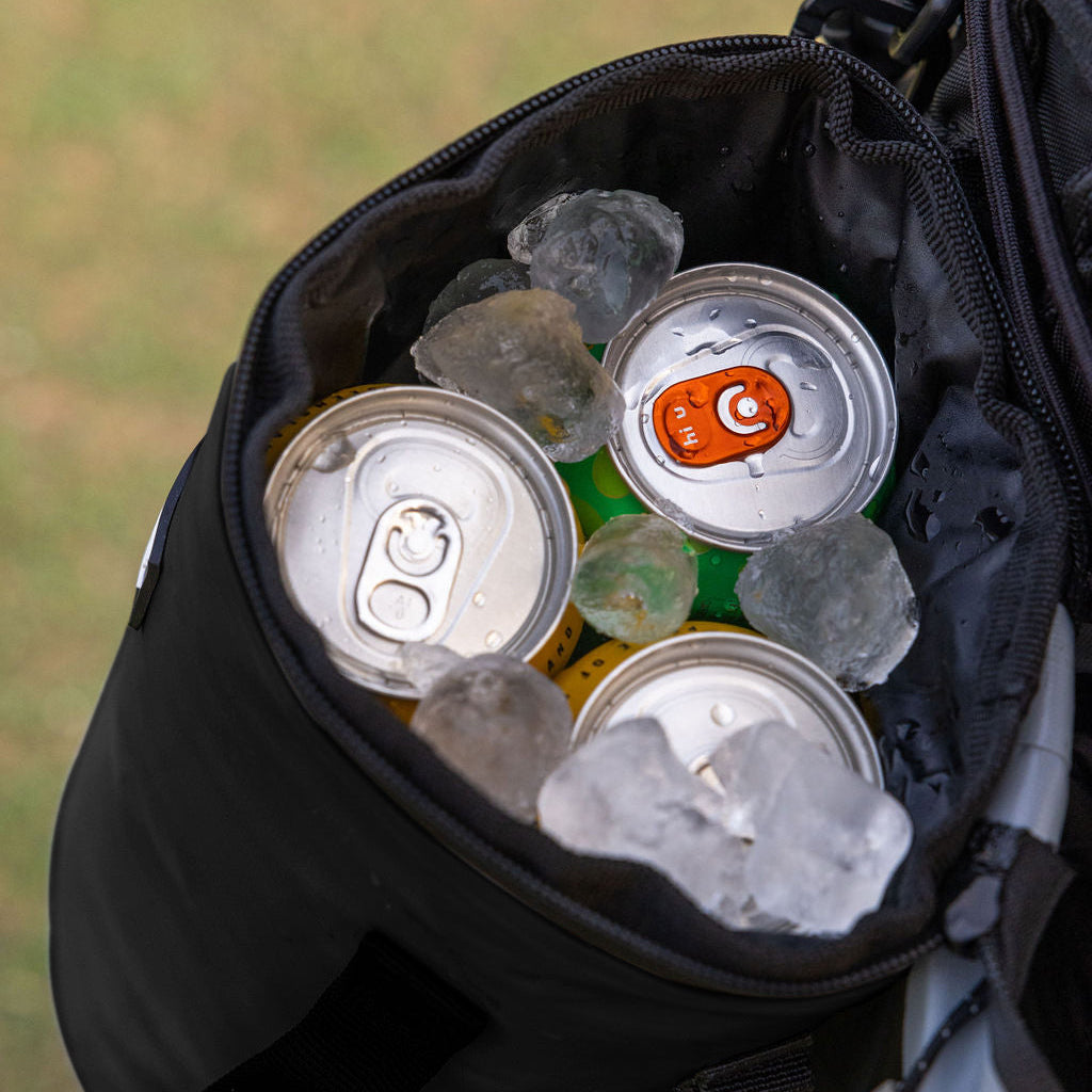 Black Tuube 2.0 cooler attached to a cart bag on a golf course, demonstrating secure carabiner clip system in a round