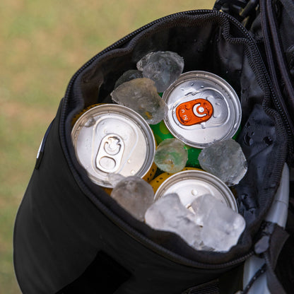 Black Tuube 2.0 cooler attached to a cart bag on a golf course, demonstrating secure carabiner clip system in a round