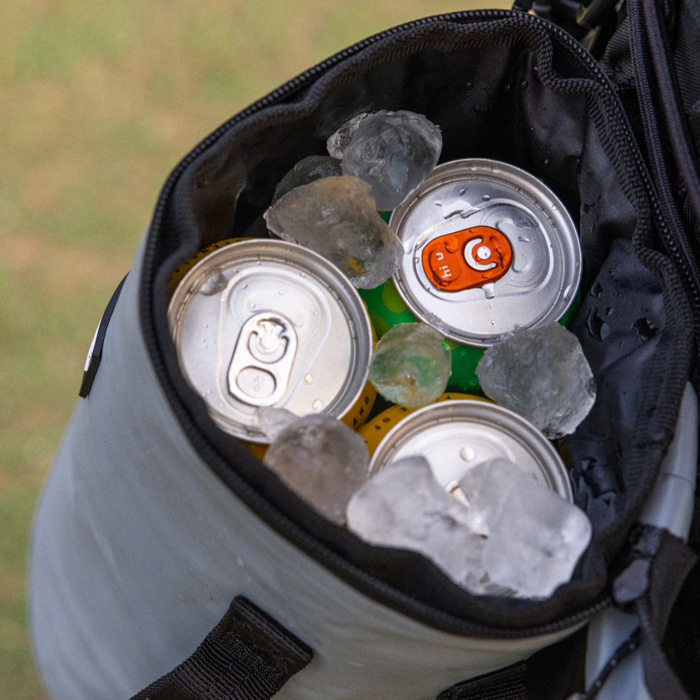 Close-up of icy cans packed inside the grey Tuube Cooler Bag 2.0, showing internal insulation keeping drinks cold during a round