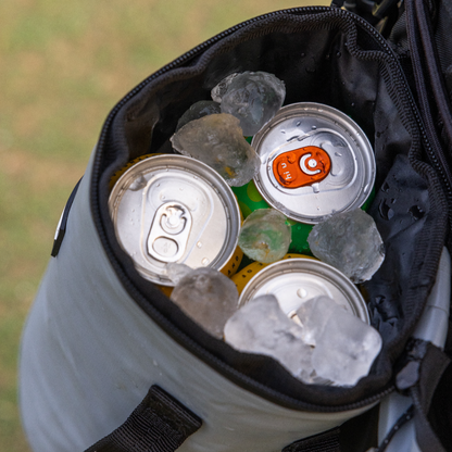 Close-up of icy cans packed inside the grey Tuube Cooler Bag 2.0, showing internal insulation keeping drinks cold during a round