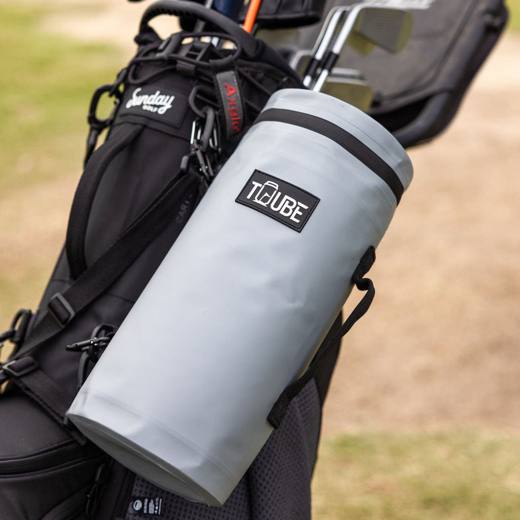 Lifestyle shot of grey Tuube 2.0 golf bag cooler in use on a golf course, demonstrating attachment to a walking golf trolley bag