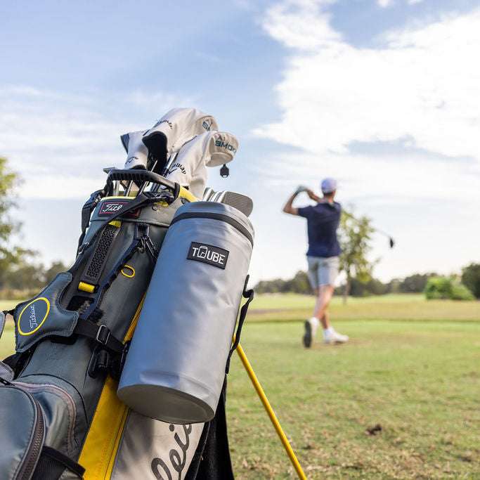 Action shot of grey Tuube Cooler Bag 2.0 secured to a golf bag on course, showing 8 looping points and nylon carry handle