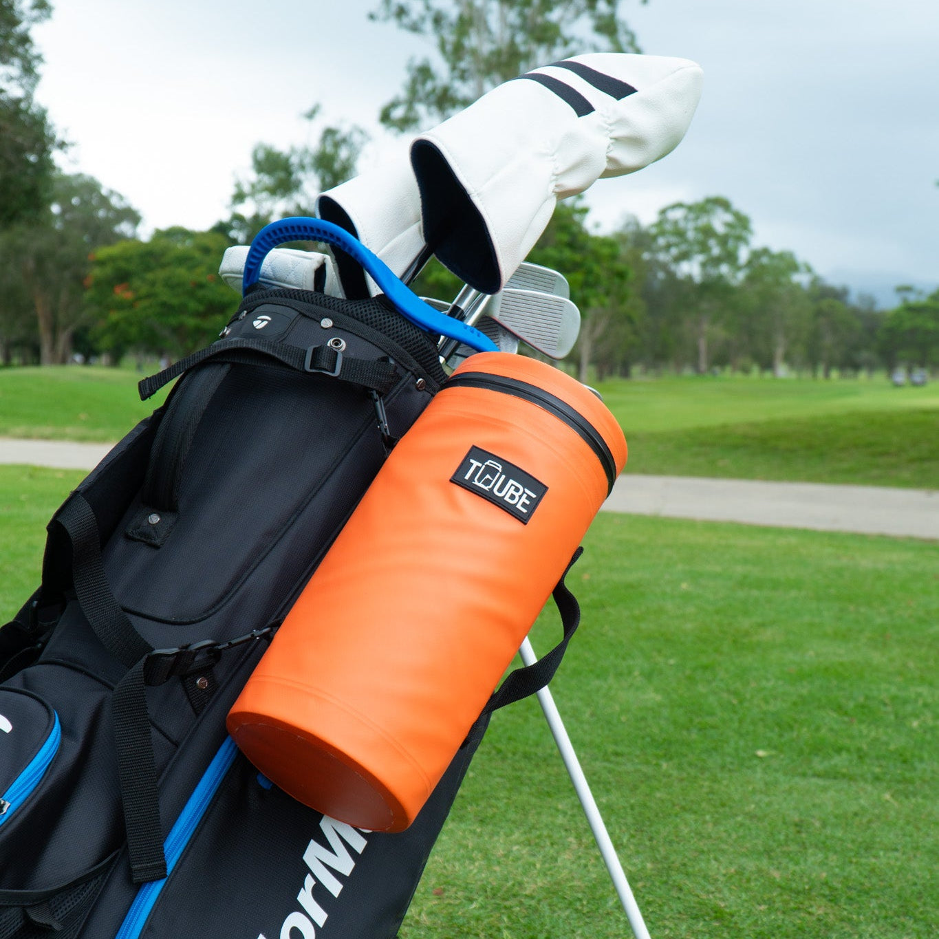 Golfer accessing drinks from orange Tuube 2.0 cooler bag during a round, demonstrating easy-access zip for cold cans