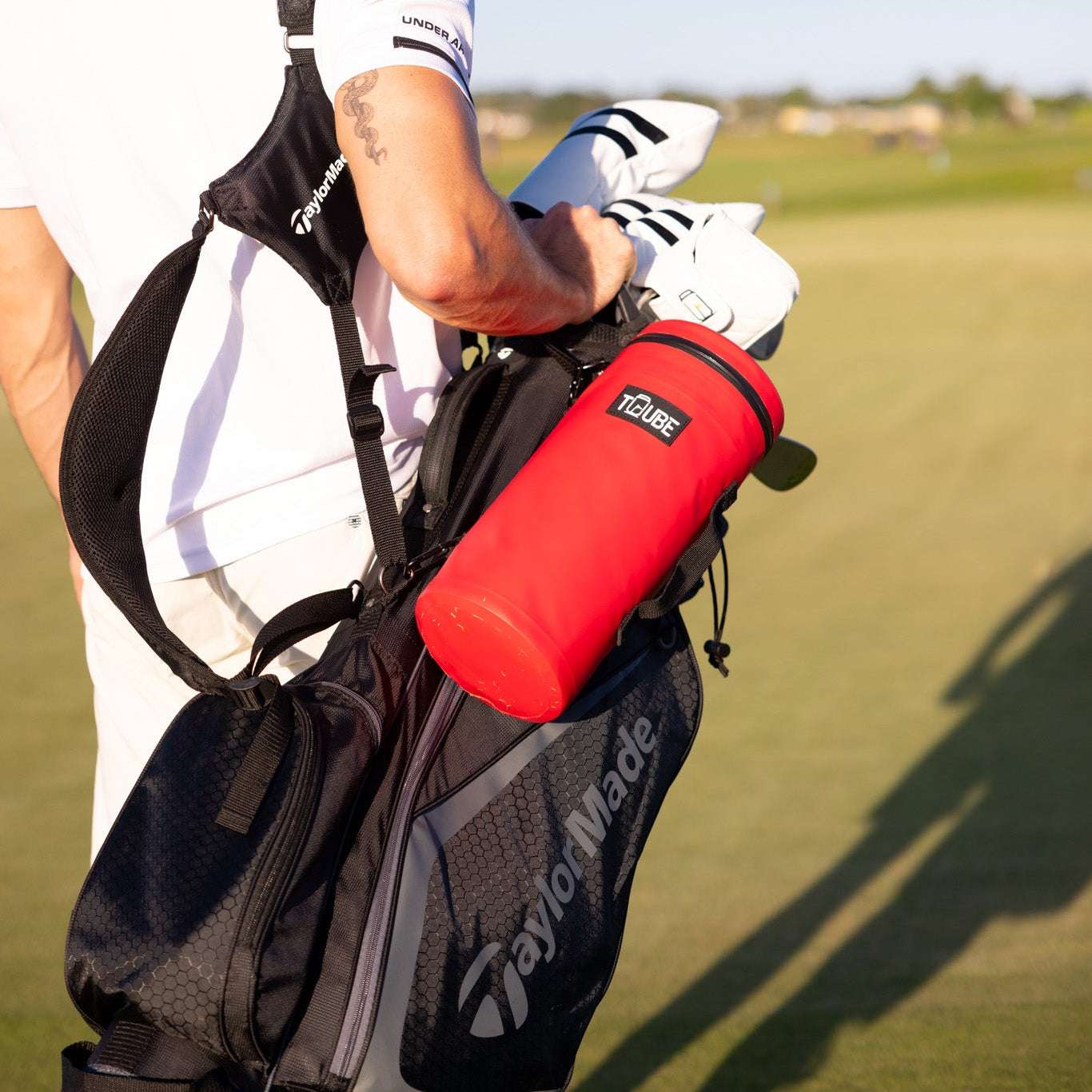 Lifestyle shot of red Tuube Cooler Bag 2.0 secured to a stand bag during a walking round, keeping drinks cold in Australian heat