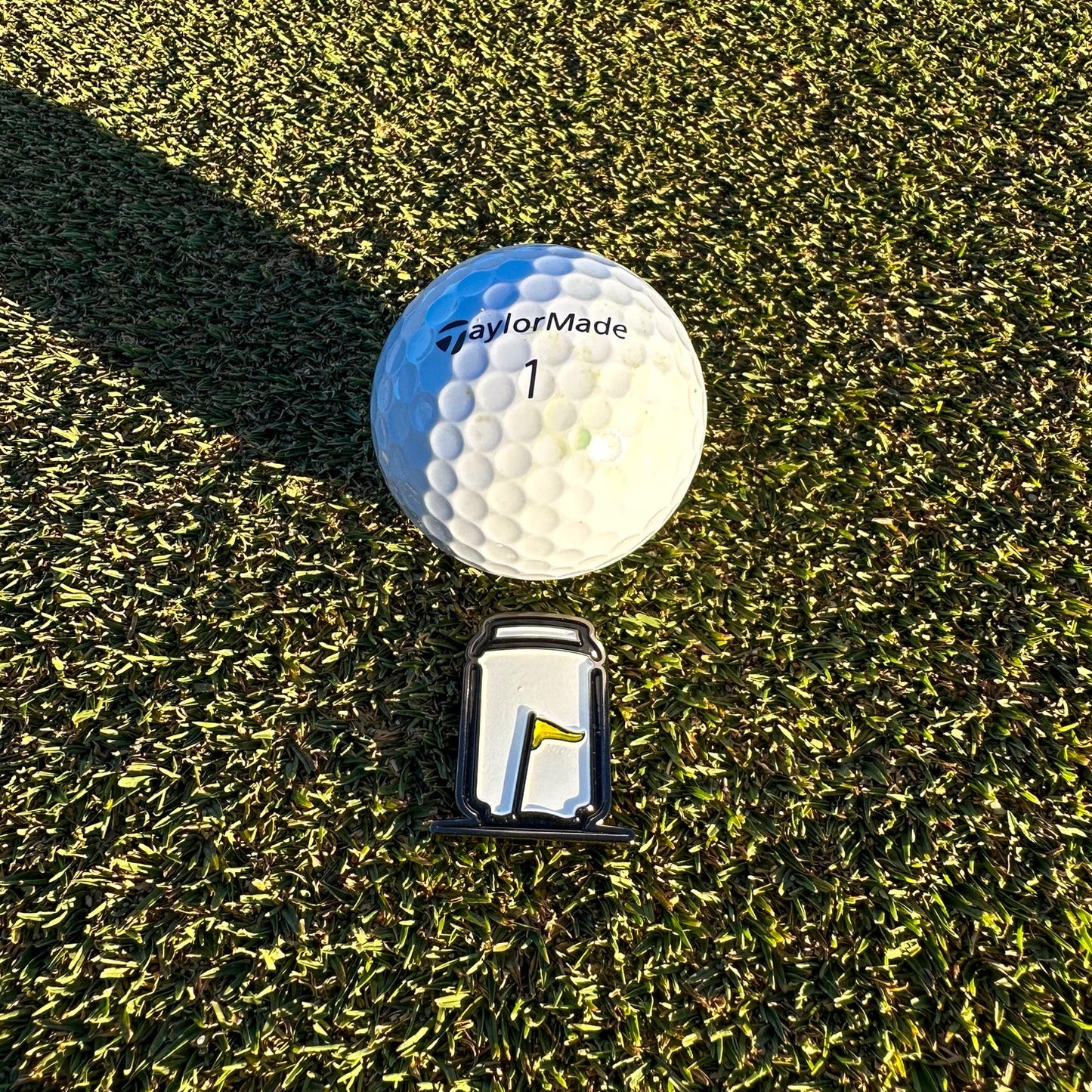 Tuube Can Ball Marker on a golf course green close-up, demonstrating how the can design adds personality to putting 