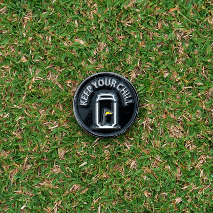Tuube Keep Your Chill ball marker photographed on a golf course, showing branded metal flat marker used during putting