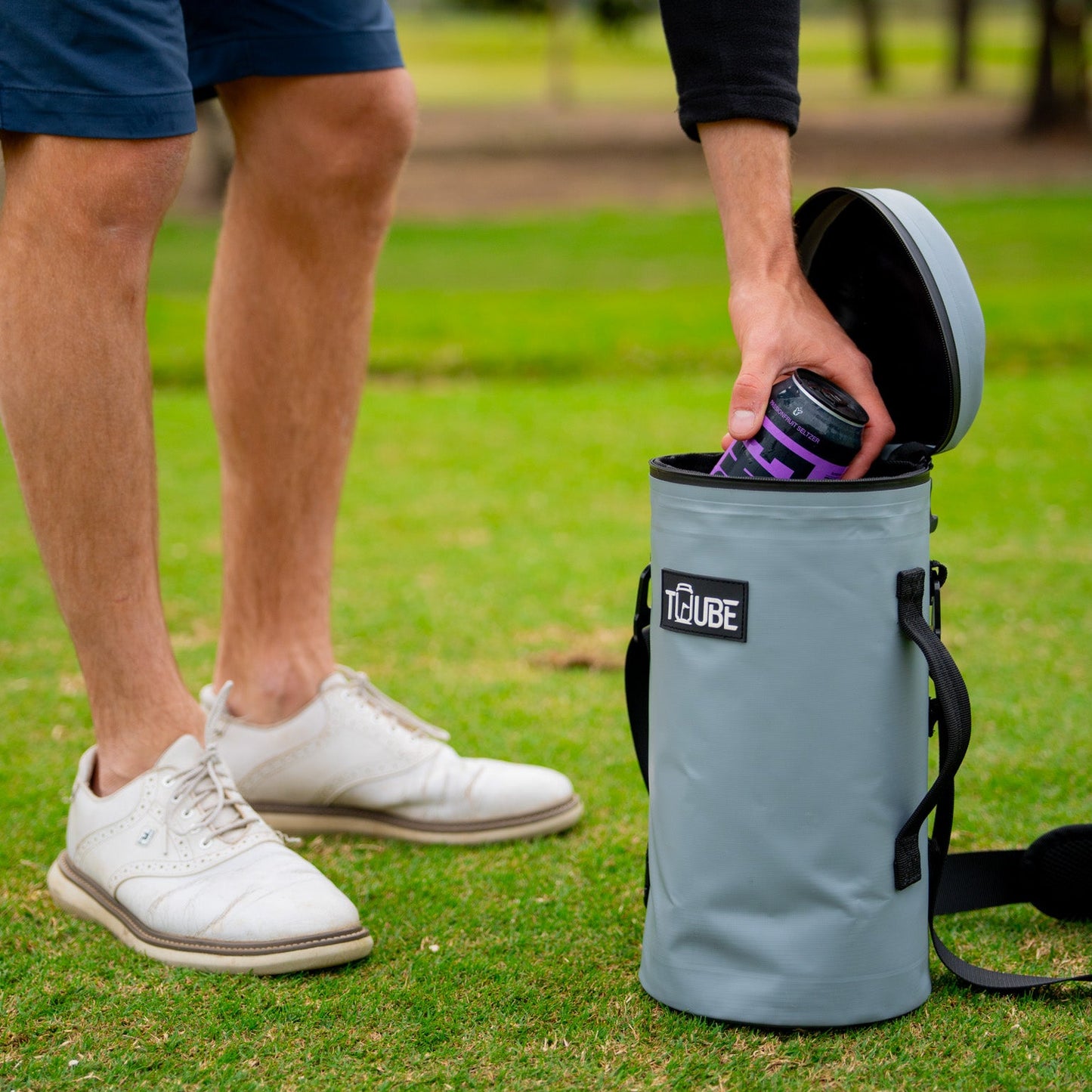 Golfer removing a chilled can from a grey Tuube XL cooler attached to their bag during a round, 8-can leakproof cooler